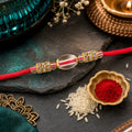 Red Thread Rakhi with Oval Crystal Bead Pendant and Golden Finish