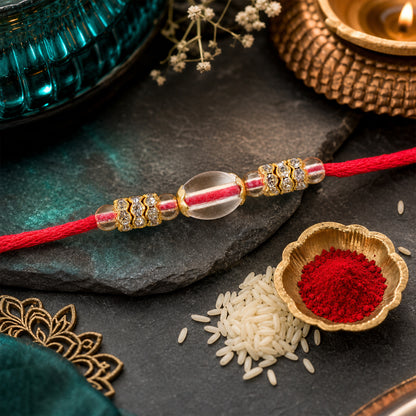 Red Thread Rakhi with Oval Crystal Bead Pendant and Golden Finish