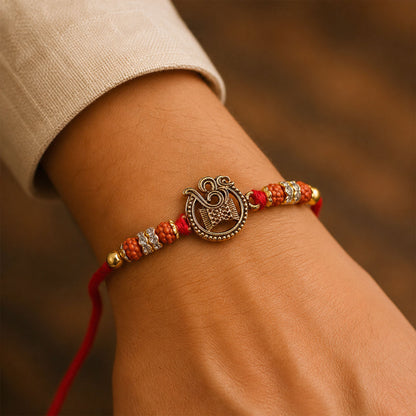 Om Damru Trishul Devotional Rakhi with Golden Centre, Orange Beads and Red Thread