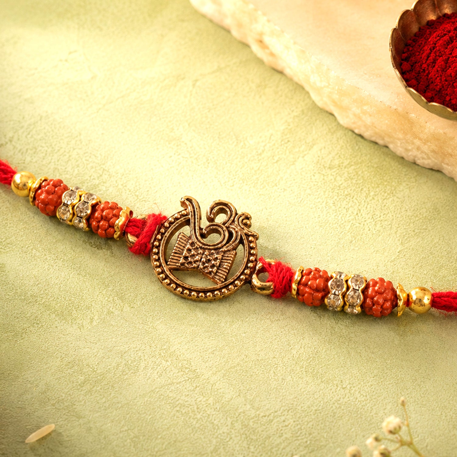 Om Damru Trishul Devotional Rakhi with Golden Centre, Orange Beads and Red Thread