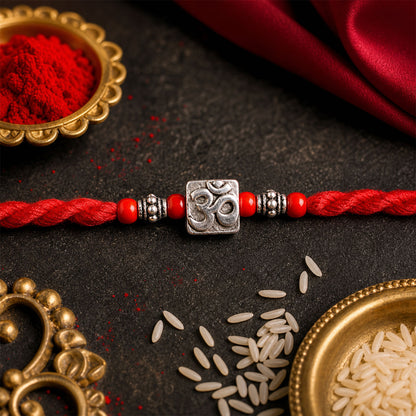 Red Thread Rakhi with a Bold Silver Om Pendant and Red Beads