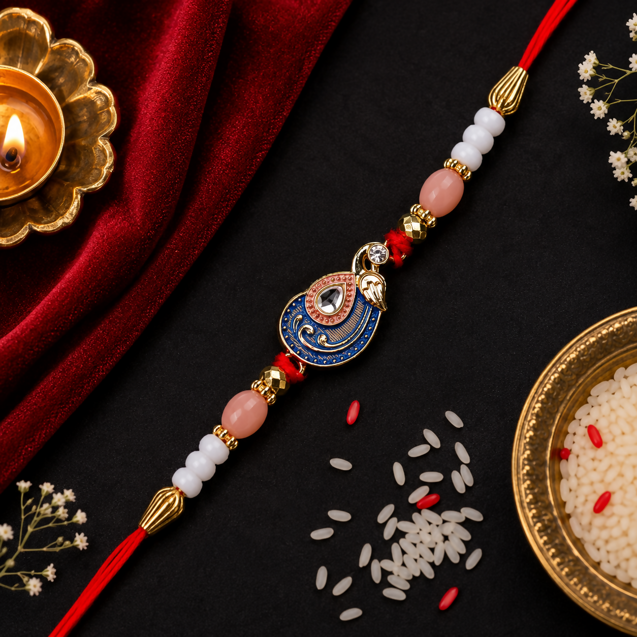 A red, blue, and gold peacock charm bracelet with pink and white beads rests on a black background with a red velvet cloth