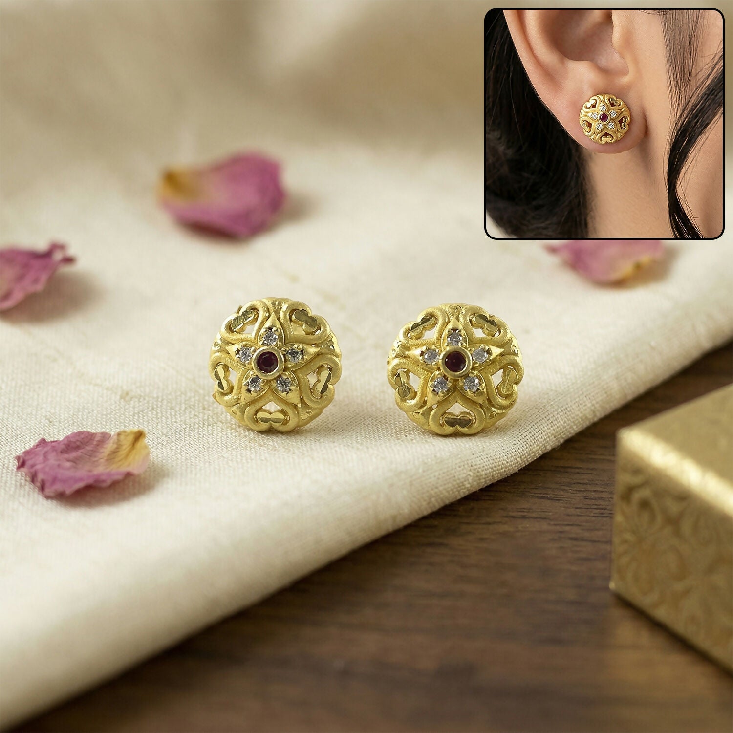 Close-up of traditional gold stud earrings with floral motifs and sparkling stones