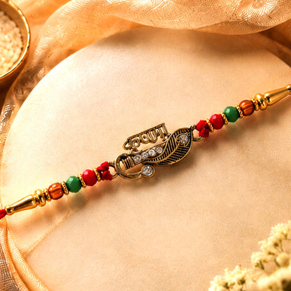 Veera Name Rakhi with Flute Leaf Style Centre, Stones and Red Green Beads