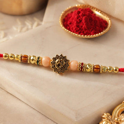 Om Sacred Symbol Golden Devotional Rakhi with Peach Beads and Red Thread