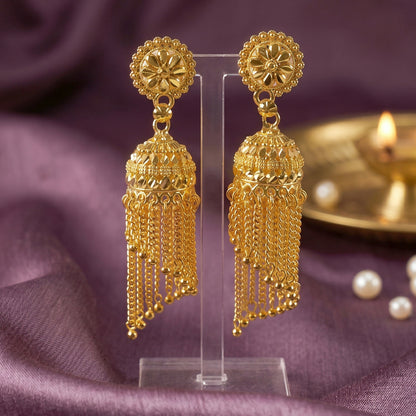 Golden jhumka earrings displayed on fabric background