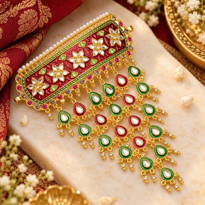 A gold-plated choker necklace with red and green meenakari floral design, featuring multiple dangling teardrop charms.