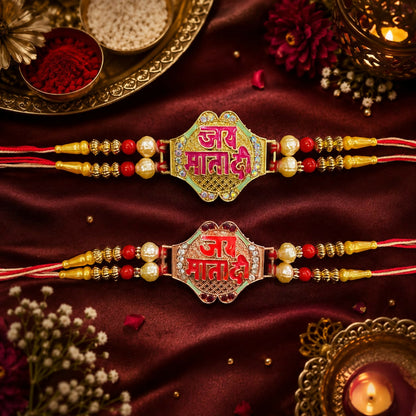 Two intricate bracelets, one green and one red, with "Jai Mata Di" text, pearls, and beads, resting on a rich red fabric.