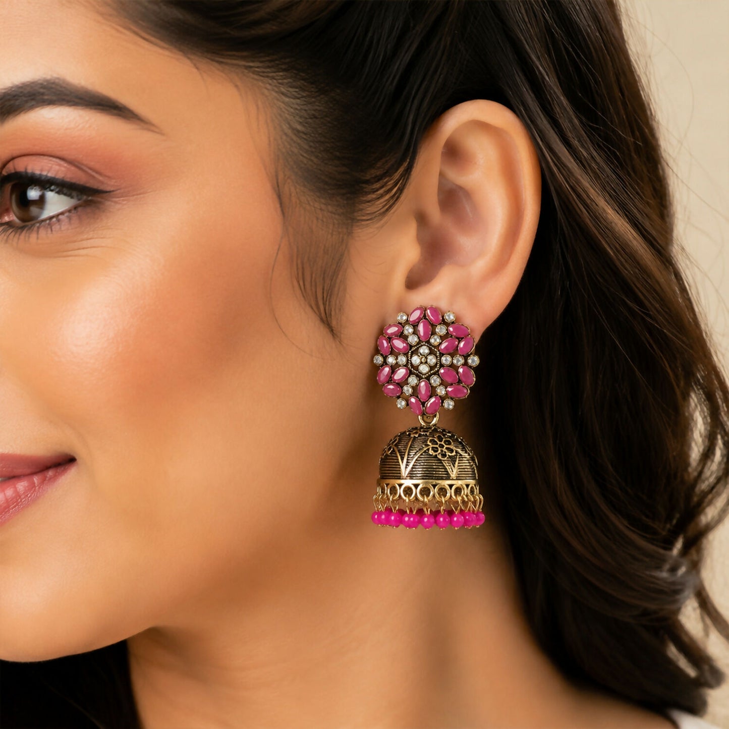 Side view of antique gold and pink stone jhumka earrings