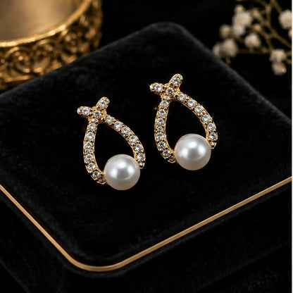 Pair of gold-tone teardrop earrings with pearl-look beads on a white surface