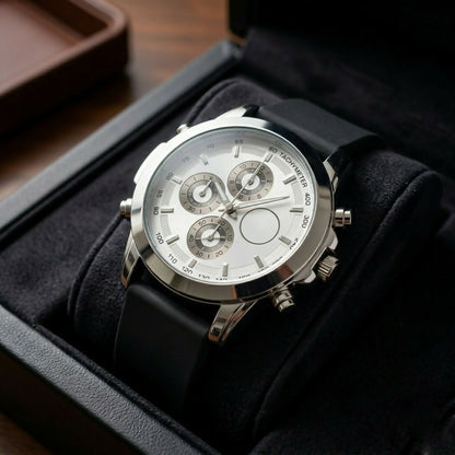 Silver chronograph watch with a white dial and black silicone strap, presented in an open black velvet box.