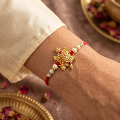Gold Turtle Charm Rakhi with Pearl Sides and Red Mauli Thread