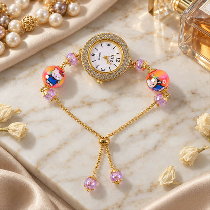 A gold-tone bracelet watch with a rhinestone-studded dial, two orange cartoon character beads, and smaller purple beads,
