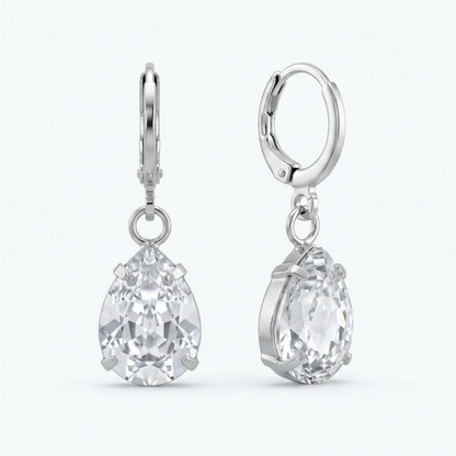 A pair of silver teardrop crystal earrings with clear faceted stones are displayed on a white background.
