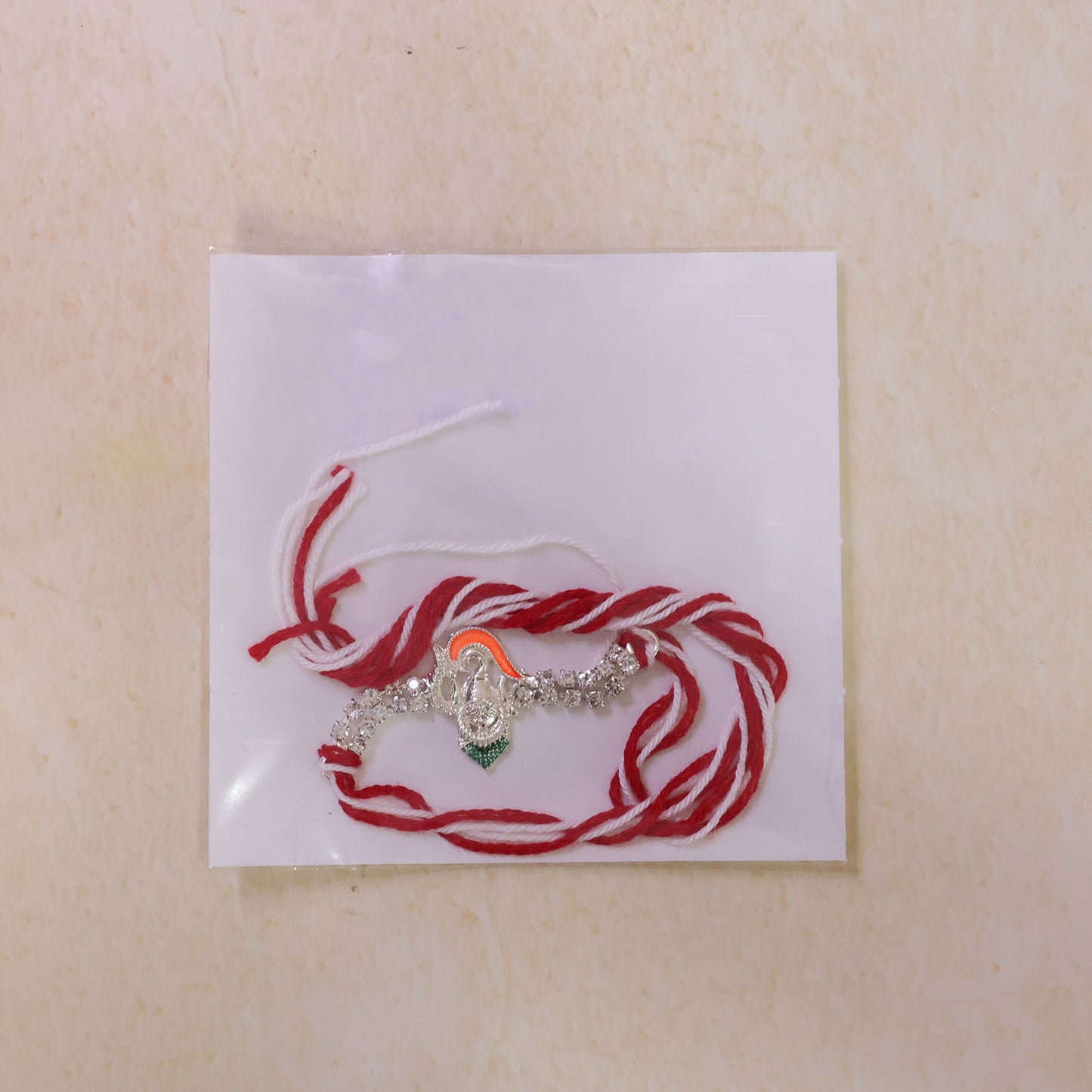 Traditional Rakhi showcasing Ganesha Charm, red stone accents and gift look for Gift