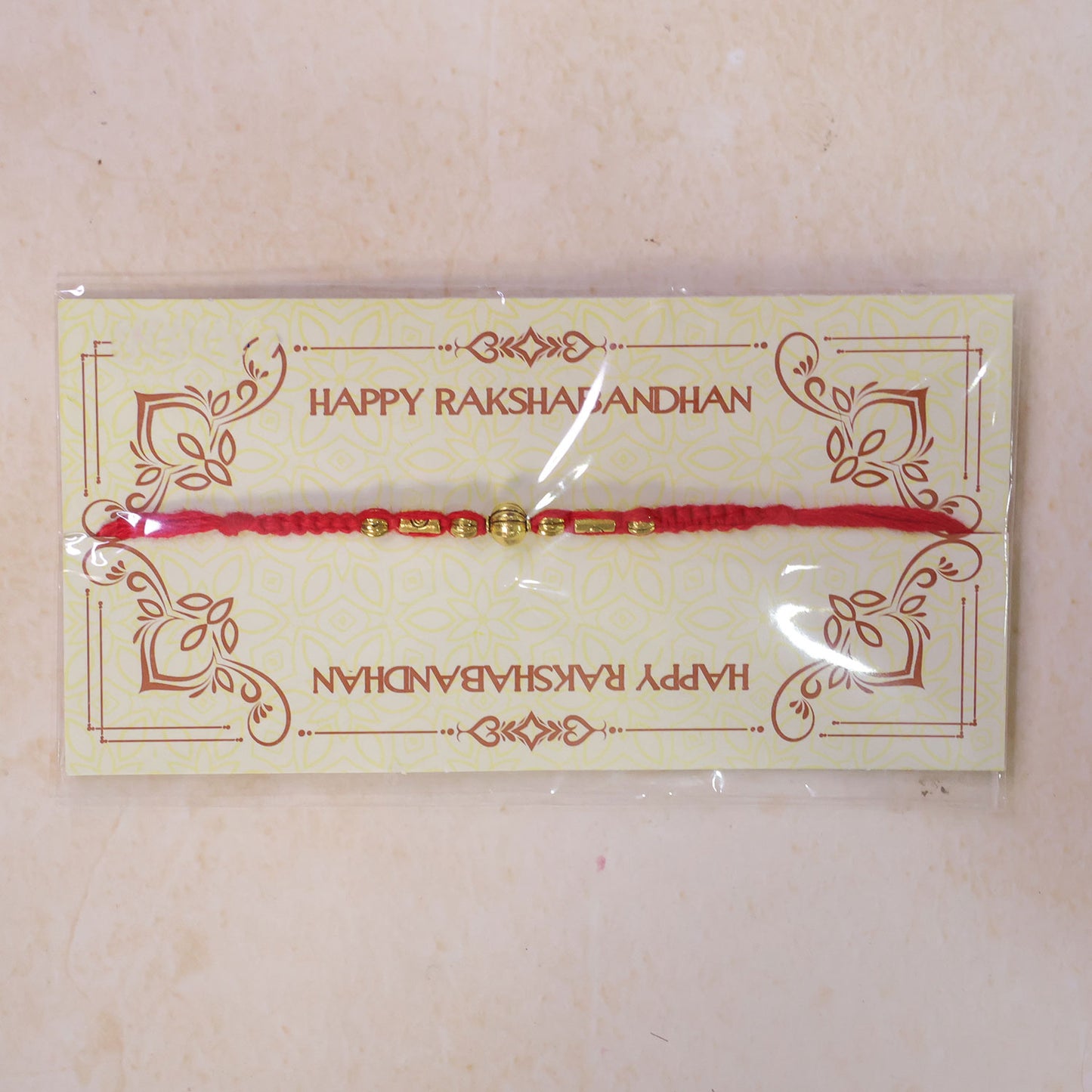 Red Braided Rakhi with a Row of Smooth Golden Bead Accents