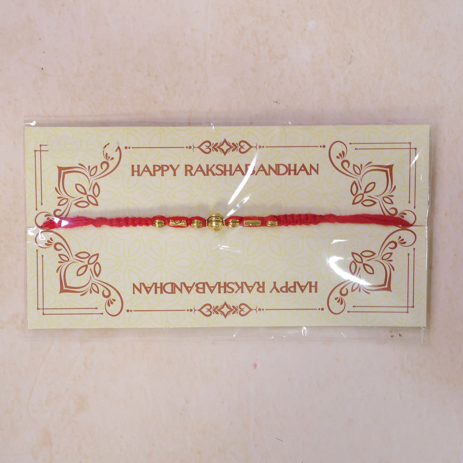 Red Braided Rakhi with a Row of Smooth Golden Bead Accents